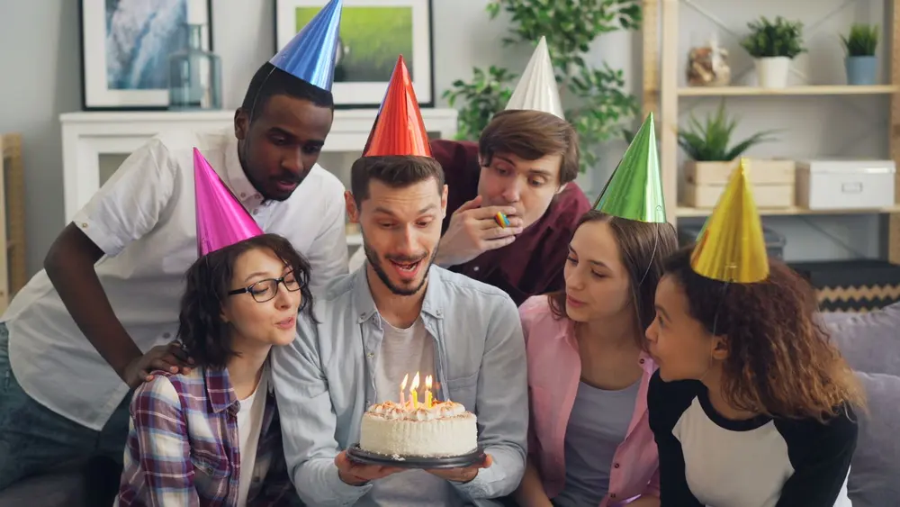 Amigos soplando las velas de una torta de cumpleaños