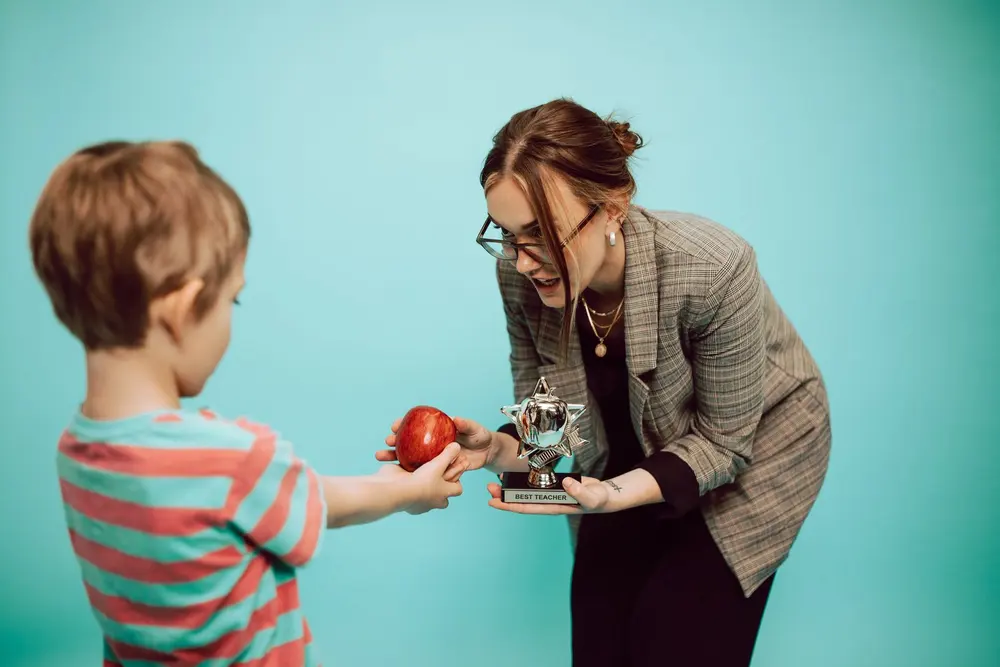 Niño entregando una manzana y un trofeo a su maestra, tazas personalizadas para promociones escolares en San Cristóbal