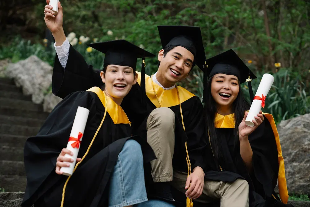 Graduandos sonriendo con birrete y diploma