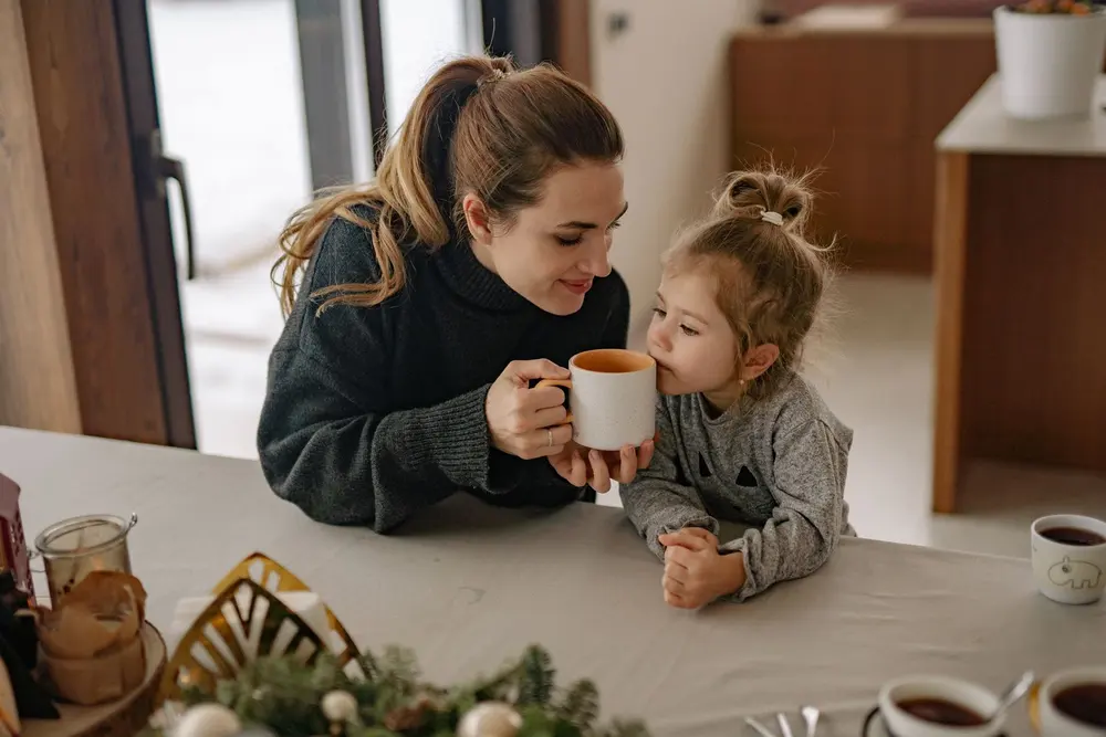 Madre e hija compartiendo una taza en casa
