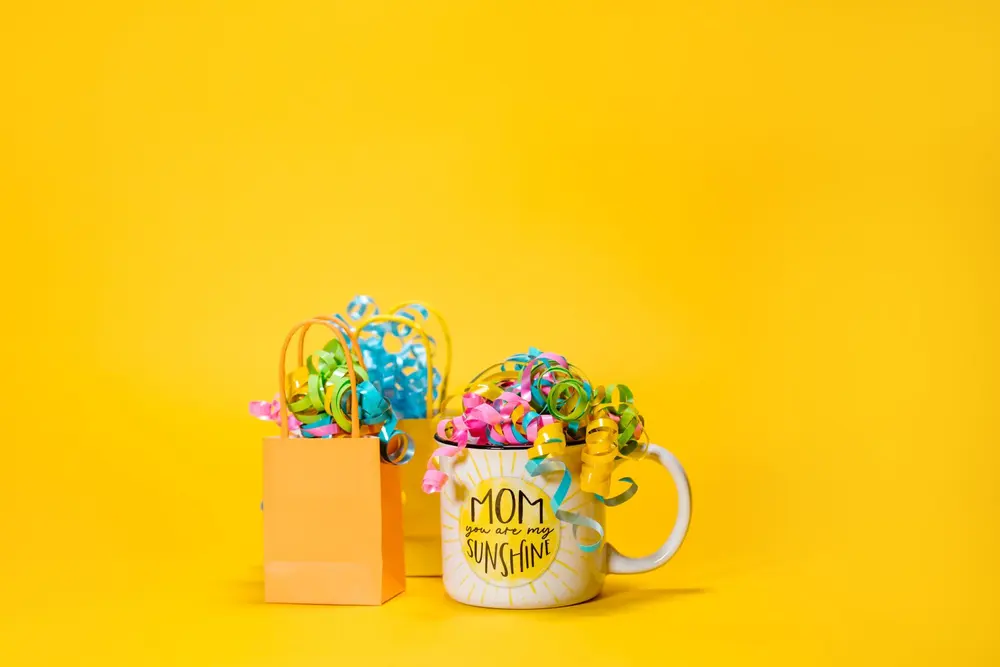 Taza «Mom» con lazos de colores sobre fondo amarillo, tazas para el día de la madre en San Cristóbal